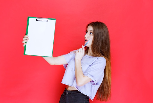 Fille tenant une feuille de rapport vierge et pensant.