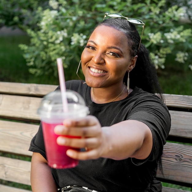 Fille tenant un smoothie devant elle à l'extérieur