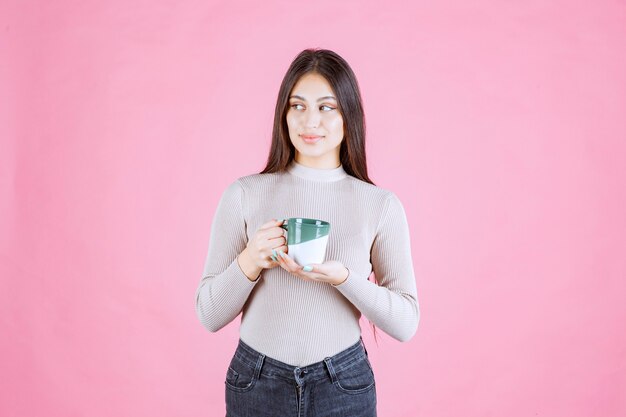 Fille tenant une tasse de café de couleur vert blanc et se sentir positif