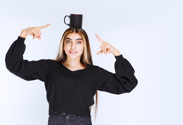 Fille tenant une tasse de café noire à la tête et se sentant satisfaite. photo de haute qualité