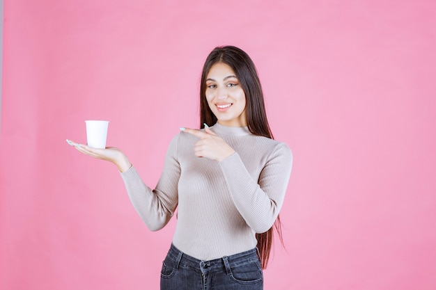 Fille tenant une tasse de café et pointant vers elle