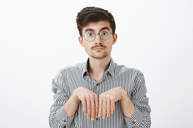 Fille transformée en petit ami en chiot. Portrait d'un homme caucasien drôle mignon avec moustache dans des verres, tenant les mains près de la poitrine comme des pattes d'animaux et regardant avec une expression insouciante et stupide