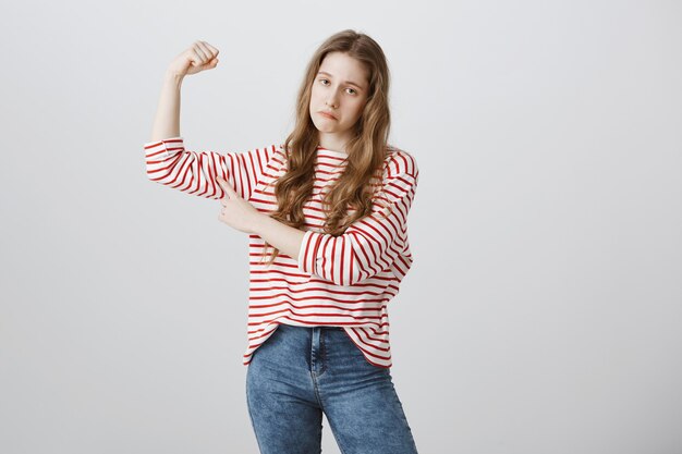 Fille triste fléchit les biceps et se plaint de sa faiblesse