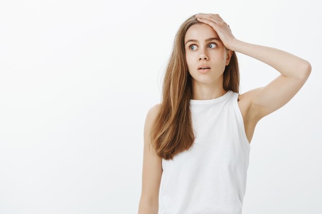 Fille troublée et épuisée, roulant les yeux et tenant la main sur la tête, dérangée par quelque chose d'ennuyeux