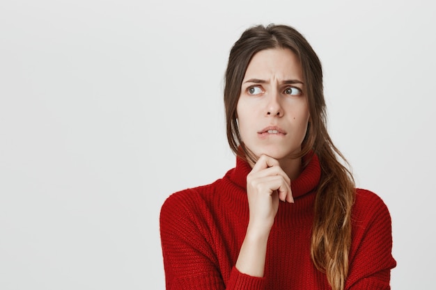 Fille troublée pensant, mordant la lèvre inquiète