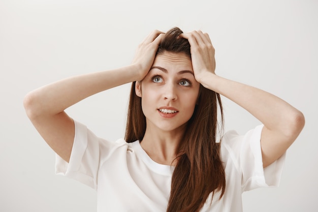 Fille troublée stupide attrape la tête et regarde inquiète