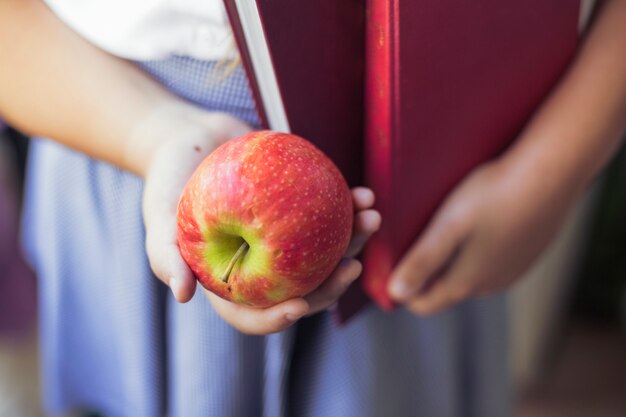 Fille en uniforme avec des pommes et des livres dans les mains