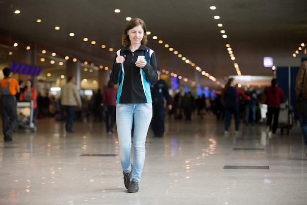 Fille utilisant un téléphone cellulaire dans l&#39;aéroport