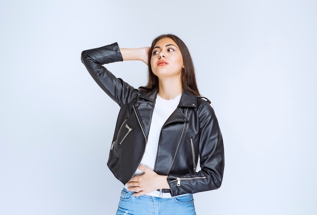 Fille en veste de cuir donnant des poses neutres et détendues.