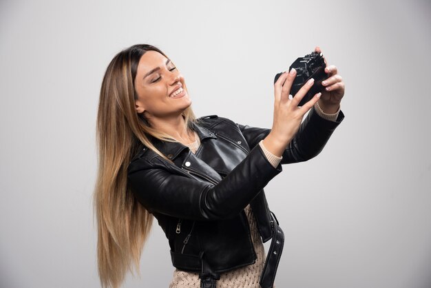 Fille en veste de cuir prenant ses photos dans des positions élégantes et positives.