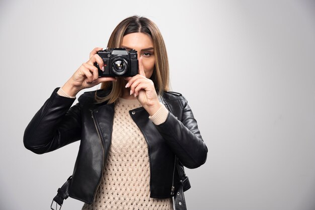 Fille en veste de cuir prenant ses photos dans des positions élégantes et positives