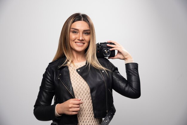 Fille en veste de cuir prenant ses photos dans des positions élégantes et positives