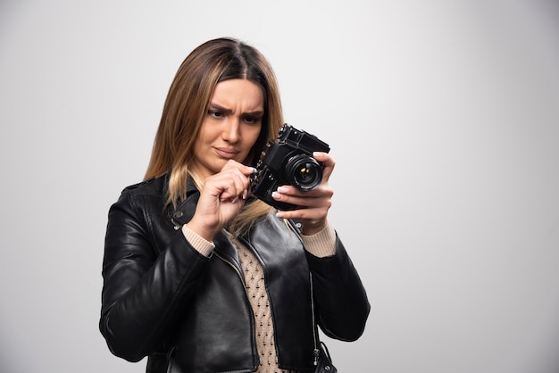 Fille en veste de cuir vérifiant l'historique des photos sur l'appareil photo et semble insatisfaite.