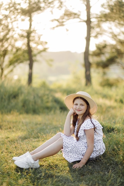 Une fille vêtue d'une robe et d'un chapeau se dresse sur le terrain