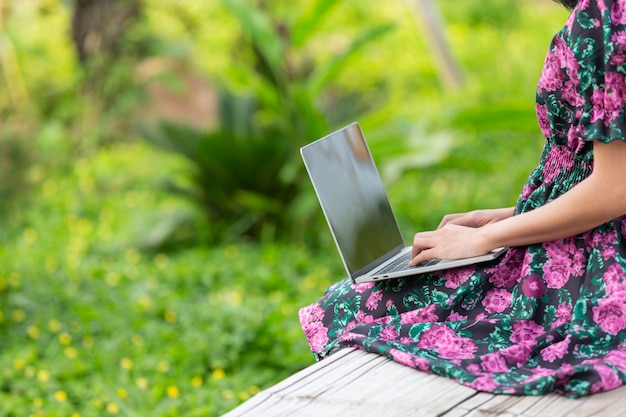 Fille vêtue d'une robe à fleurs assise avec son ordinateur portable