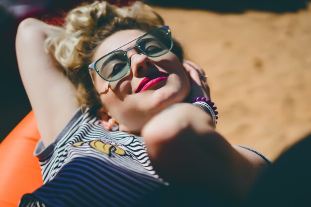 fille en vintage lunettes de soleil avec des tatouages ​​portrait gros plan sur la rue lors d&#39;un pique-nique avec des amis. Chill fille