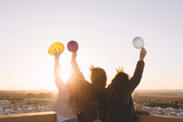 Filles anonymes avec des ballons sur le toit