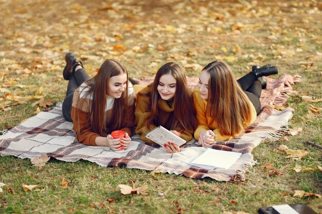 Filles assis sur une couverture dans un parc en automne