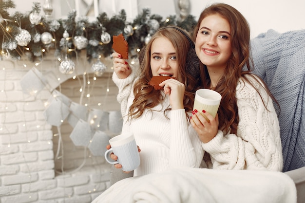 Filles assises sur la chaise. Femmes avec des tasses. Sœurs se préparent pour Noël