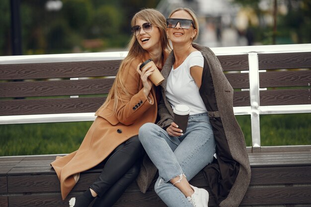 Filles assises dans un printemps sity et tiennent le café dans sa main