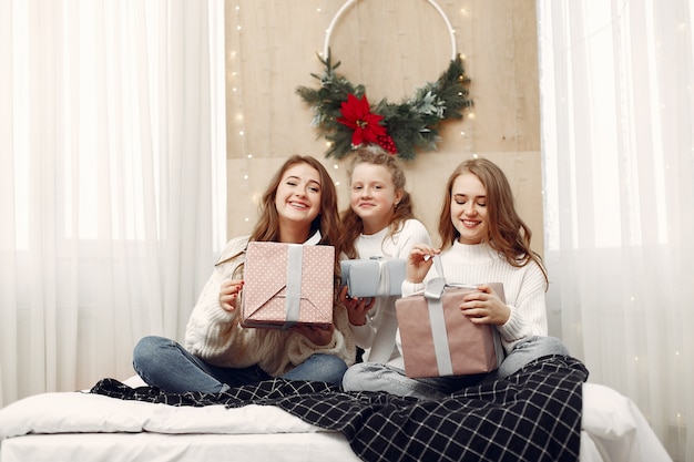 Filles assises sur le lit. Les femmes avec des coffrets cadeaux. Les amis se préparent pour Noël.