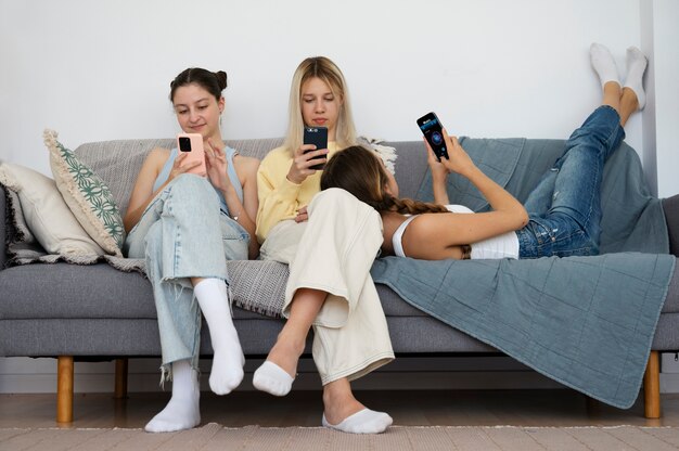 Filles sur canapé avec smartphones plein coup