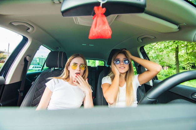 Filles choquées en conduisant une voiture. Vacances d'été