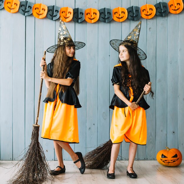 Filles en costumes de sorcière tenant des balais