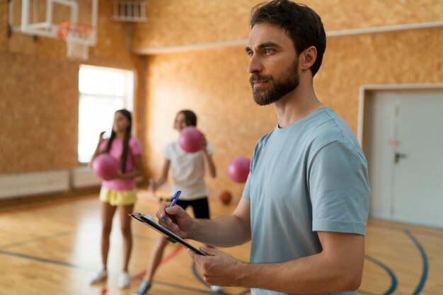 Filles de coup moyen et professeur au gymnase