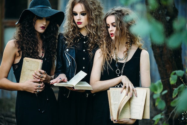 Les filles déguisées en sorcières tenant vieux livres ouverts en mains
