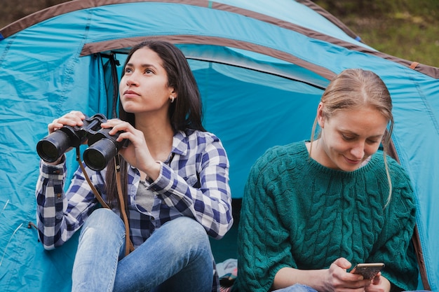 Des filles distraits avec des jumelles et un téléphone mobile