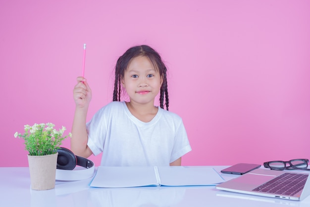 Les filles écrivent des livres sur un fond rose.