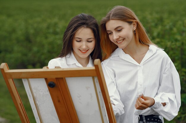 Filles élégantes et belles peignant dans un champ