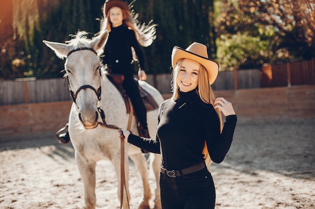 Filles élégantes avec un cheval dans un ranch