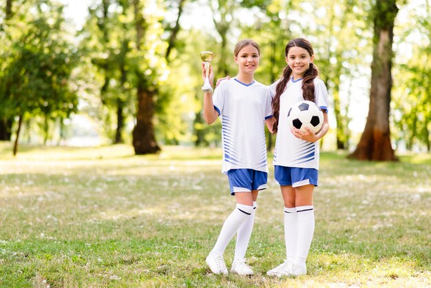 Filles en équipement de football posant avec espace copie