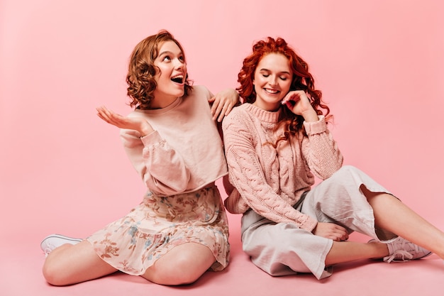 Filles excitées riant sur fond rose. Photo de Studio d'amies exprimant le bonheur.