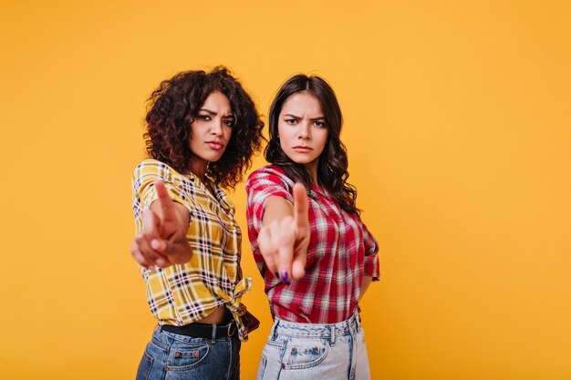 Les filles avec une expression de visage sévère montrent un panneau d'arrêt. Les copines regardent avec reproche, montrant les index