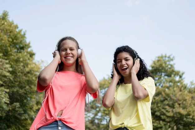 Photo gratuite filles à faible angle écoutant de la musique