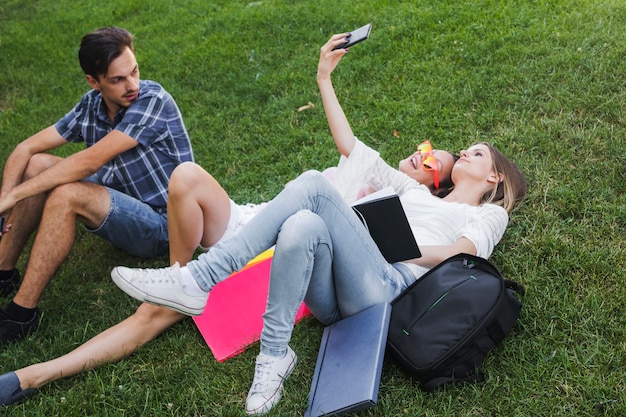 Des filles gaies qui prennent une photo près du camarade de classe