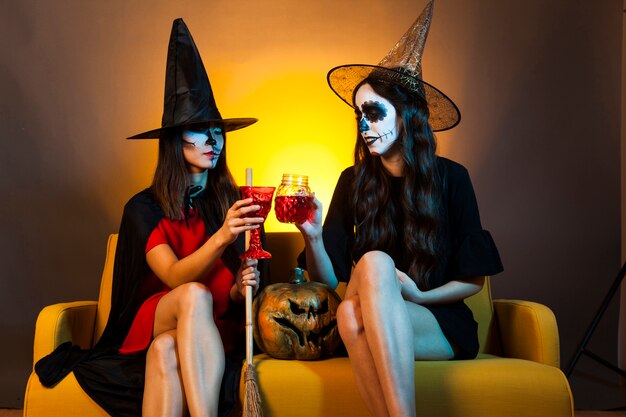 Les filles de Halloween au canapé avec des boissons