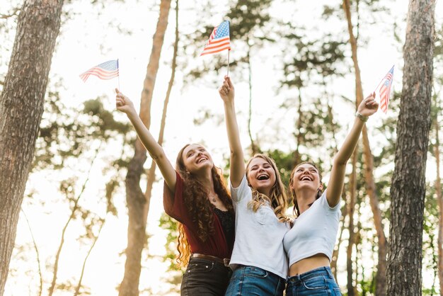 Filles joyeuses dans la nature avec des drapeaux américains