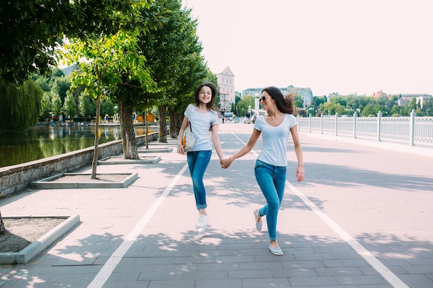 Les filles marchant sur le trottoir se tenant la main