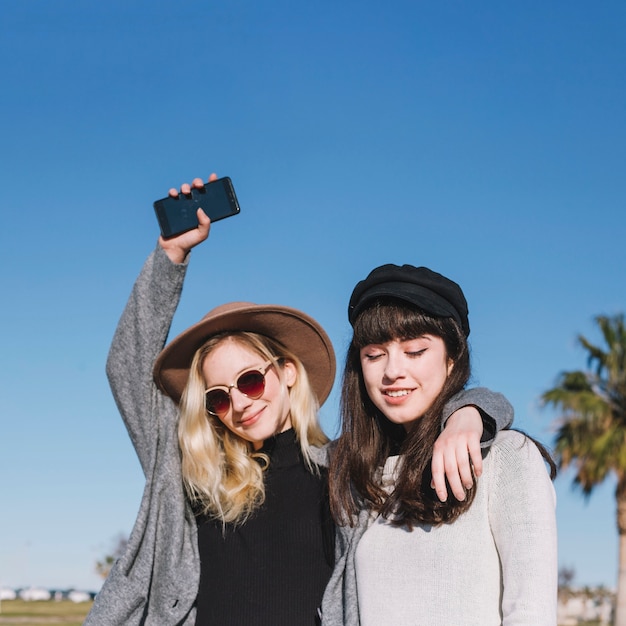 Filles modernes élégantes posant joyeusement sur la rue