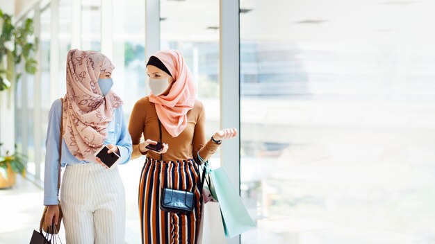 Filles musulmanes traînant dans des masques faciaux au centre commercial