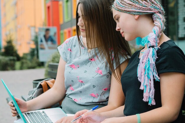 Filles avec ordinateur portable sur banc