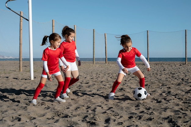 Filles pleines jouant au football sur la plage