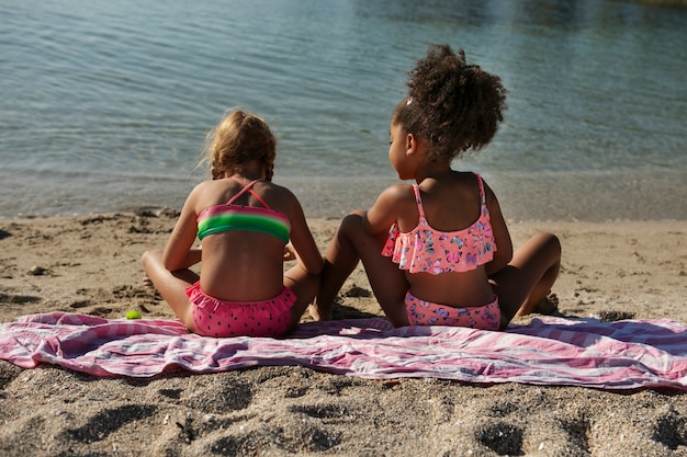 Photo gratuite filles pleines de tir assis sur la plage