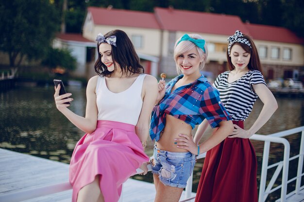 Les filles posant sur une balustrade blanche et un en regardant son téléphone mobile