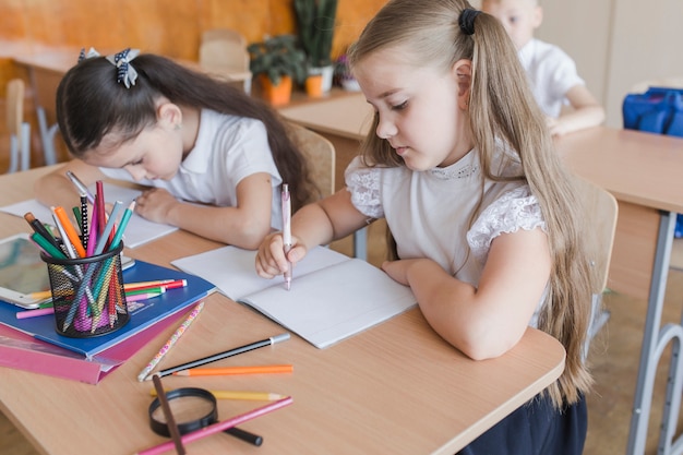 Filles remplissant l&#39;exercice dans le cahier