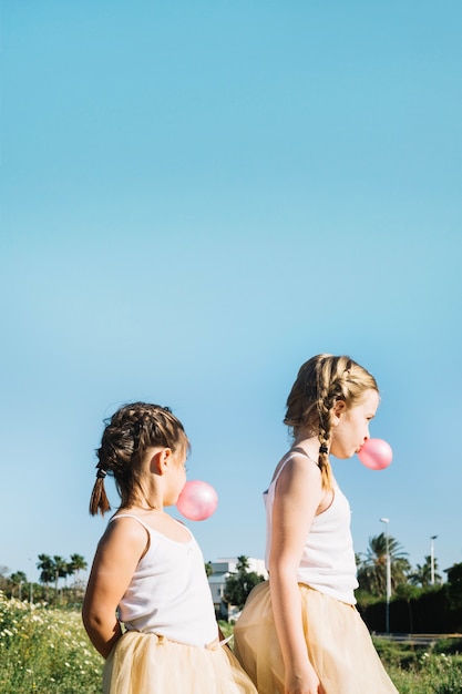 Filles soufflant des gommes à bulles dans le champ